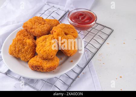 Nuggets de poulet frits dorés traditionnels sur une assiette, avec sauce ketchup. Banque D'Images