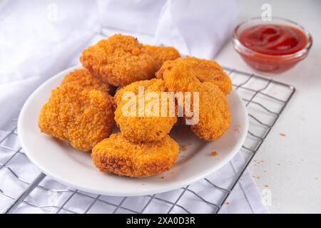 Nuggets de poulet frits dorés traditionnels sur une assiette, avec sauce ketchup. Banque D'Images