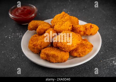 Nuggets de poulet frits dorés traditionnels sur une assiette, avec sauce ketchup. Banque D'Images