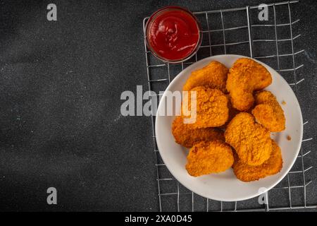 Nuggets de poulet frits dorés traditionnels sur une assiette, avec sauce ketchup. Banque D'Images