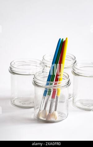 Les pinceaux assortis dans un pot en verre sur fond blanc Banque D'Images
