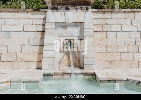 Un mur de pierre et une clôture en briques entourent une fontaine Banque D'Images