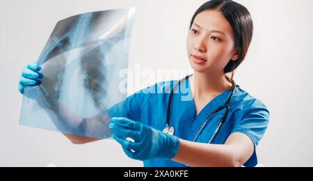 Diagnostic médical. Radiographie thoracique. Femme médecin étudiant la radiographie des poumons résultat dans la main concentré scanner établir le diagnostic prescrire le traitement isolé sur blanc. Banque D'Images