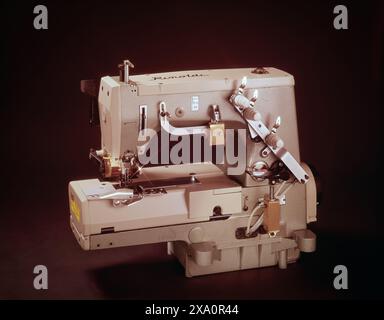 Machine à coudre industrielle, présentant l'ingénierie de précision, les composants métalliques et le mécanisme de fil sur fond sombre. Banque D'Images