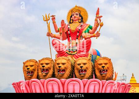 Statue bleue du Seigneur Shiva assise avec une peau de tigre, tenant un trident et affichant un geste de bénédiction. Orné de serpents et de perles, ce vibrant Banque D'Images