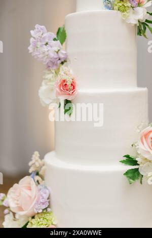 Un élégant gâteau de mariage blanc orné de fleurs Banque D'Images