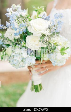 Un pont tenant un bouquet de fleurs blanches et bleues dans ses mains Banque D'Images