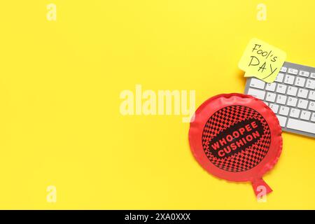 Clavier d'ordinateur, note collante et coussin whoopee sur fond jaune. Farce du jour des fous d'avril Banque D'Images