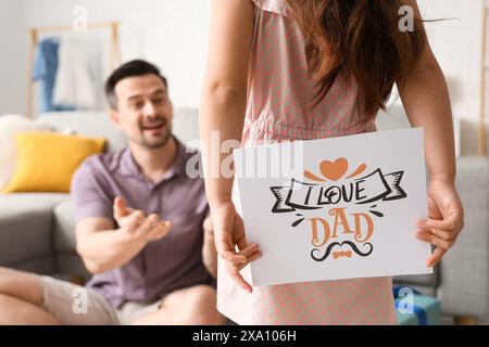 Fille faisant la surprise à son père et tenant du papier avec du texte I LOVE PAPA. Célébration de la fête des pères Banque D'Images