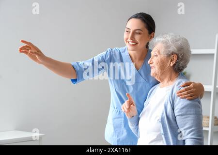 Femme senior avec physiothérapeute embrassant à la maison Banque D'Images