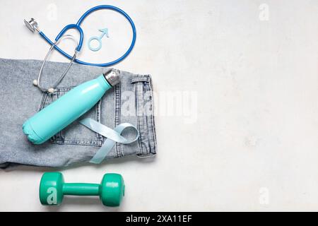 Jeans, stéthoscope, haltère, signe masculin et ruban bleu clair sur fond blanc. Sensibilisation au cancer de la prostate Banque D'Images