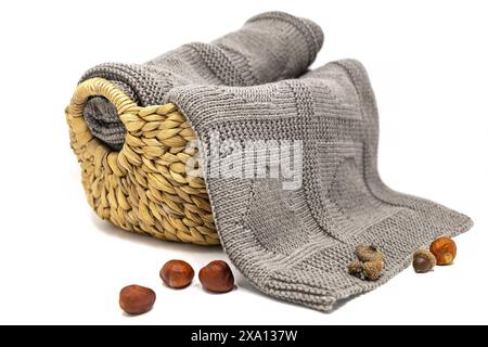 photographie d'une couverture de laine brune tricotée à la main en motif de tricot de coeurs dans un panier isolé sur un fond blanc Banque D'Images