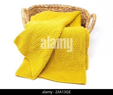 photographie d'une couverture tricotée en laine jaune en motif de tricot diamant dans un panier isolé sur un fond blanc Banque D'Images