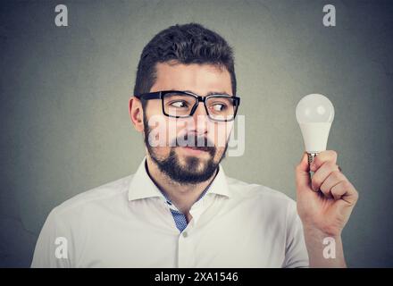 Homme regardant une ampoule économe en énergie Banque D'Images