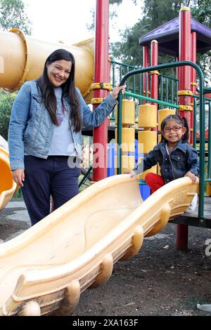 Maman célibataire divorcée et brune Latina fille de 4 ans jouer dans les jeux du parc dans la pauvreté et la solitude passer du temps de qualité dans leur repos Banque D'Images