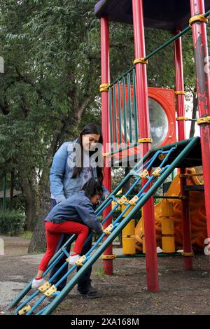 Maman célibataire divorcée et brune Latina fille de 4 ans jouer dans les jeux du parc dans la pauvreté et la solitude passer du temps de qualité dans leur repos Banque D'Images