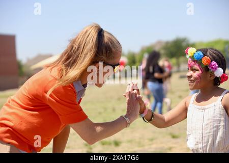 Une femme serrant la main avec une fille portant un bracelet en caoutchouc Banque D'Images