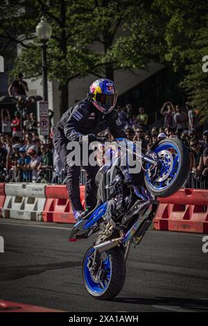 Un homme sur une moto bleue séduit la foule avec des tours Banque D'Images