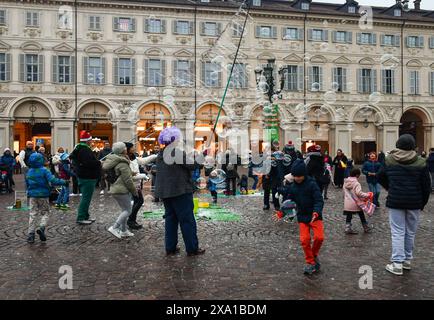 Des artistes de rue divertissent un groupe d'enfants créant des bulles de savon géantes sur la Piazza San Carlo, l'une des principales places de Turin, Piémont, Italie Banque D'Images