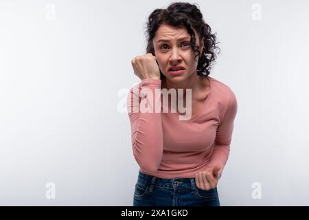 Brunette Curly Woman doute et s'inquiète. Concept d'émotions négatives Banque D'Images