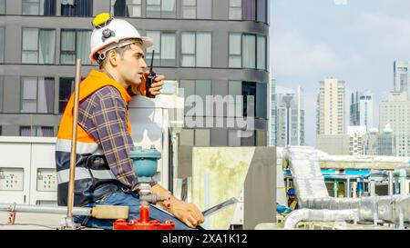 Travailleur en équipement de sécurité avec ordinateur portable et talkie-walkie sur le chantier de construction Banque D'Images