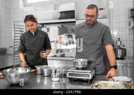 Femme et homme en pâte à pétrir uniforme dans la cuisine préparant la pâtisserie dans le restaurant Banque D'Images