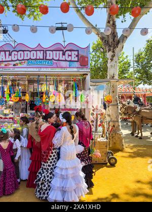 Les festivaliers en tenue traditionnelle à Feira de Abril à Séville font la queue chez un vendeur sucré pendant la semaine du festival Banque D'Images