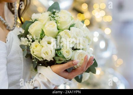 La femme tenant un bouquet de mariage avec un fond de bokeh doré Banque D'Images