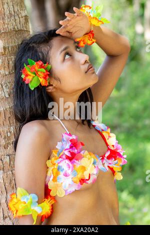 Danseuse de hula hawaïenne reposant sous un palmier Banque D'Images