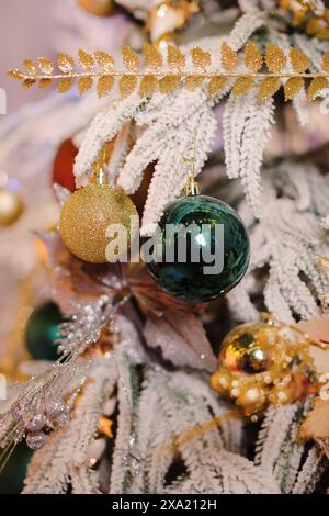 Un sapin de Noël joliment décoré avec des ornements dorés, des lumières et des décorations suspendues Banque D'Images