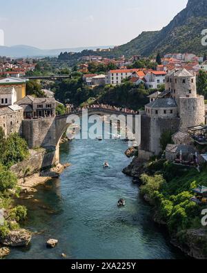 Cette photo capture une rivière qui traverse la ville de Mostar, avec un vieux pont en relief en arrière-plan, en Bosnie-Herzégovine Banque D'Images