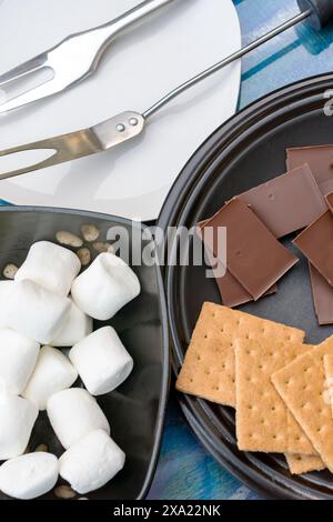 Ingrédients pour faire des smores.. Vue de dessus avec chocolat, biscuits graham, guimauves et fourchettes pour rôtir des guimauves. Banque D'Images