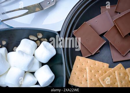 Ingrédients pour faire des smores.. Vue de dessus avec chocolat, biscuits graham, guimauves et fourchettes pour rôtir des guimauves. Banque D'Images