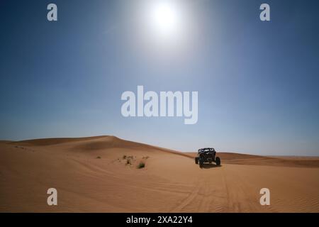 Une personne conduisant une jeep à travers des dunes de sable en plein soleil Banque D'Images