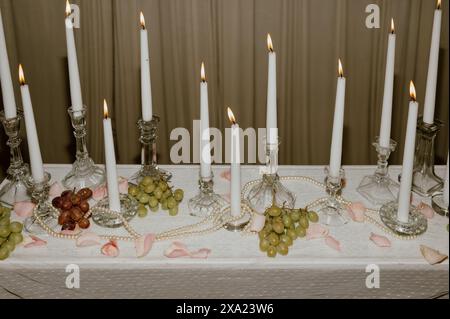Un chandelier et des cônes blancs allumés avec des raisins, des perles et des pétales de rose rose. Banque D'Images