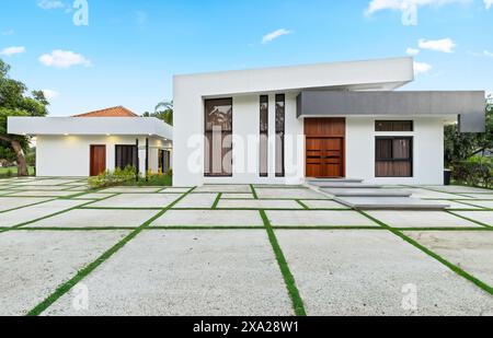 Une façade de maison blanche contemporaine avec jardin avant et entrée avec carreaux de béton Banque D'Images