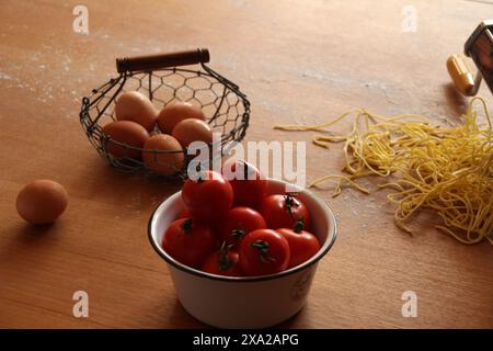 Ingrédients frais pour un délicieux repas : œufs, tomates et pâtes, affichés à côté de deux paniers sur une table Banque D'Images