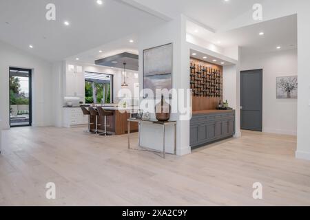 Une cuisine blanche avec îlot et plusieurs chaises dans une nouvelle maison de construction moderne à Los Angeles Banque D'Images