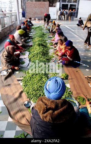 Les bénévoles travaillent dans la cuisine du Temple d'Or coupant des légumes ou cuisinant des chapatis. Amritsar, Inde. Banque D'Images