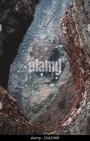 Cette superbe photographie capture les eaux claires d'un bassin de marée niché parmi les rochers accidentés d'Afrique du Sud. Les détails complexes et la beauté naturelle Banque D'Images