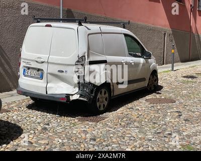 Cremona, Italie - 2 mai 2024 L'arrière d'un fourgon de travail blanc, fortement endommagé après un accident. La camionnette est garée dans une rue pavée, en attente de représentation Banque D'Images