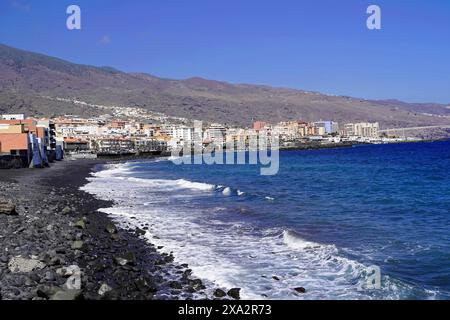 Plage volcanique noire à Candelaria, Tenerife, Îles Canaries, Espagne, Europe, vue sur une ville côtière avec des bâtiments le long de la côte et des vagues qui s'écrasent Banque D'Images