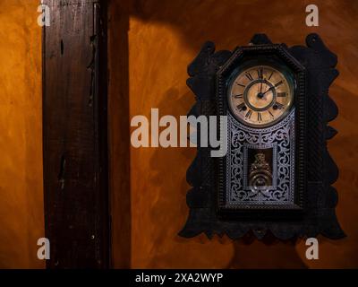 Vieille horloge pendulaire en bois accrochée au mur rouge Banque D'Images