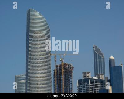 Gratte-ciel et gratte-ciel avec une grue en phase de construction sous un ciel bleu clair, Abu Dhabi, Émirats arabes Unis Banque D'Images