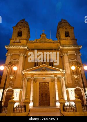 Façade d'église illuminée la nuit, avec deux tours, lampes et éléments décoratifs, Valette, Malte Banque D'Images