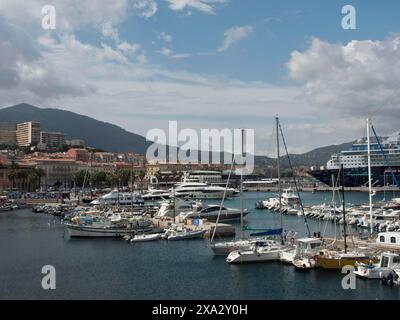 Vue sur le port avec de nombreux bateaux et yachts devant un paysage montagneux et sous un ciel nuageux, Corse, Ajaccio, France Banque D'Images