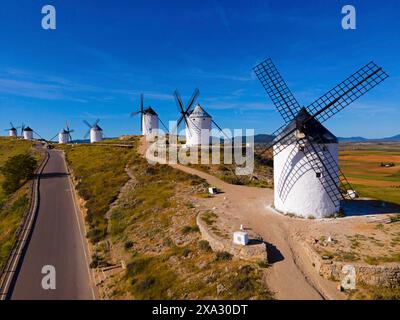 Série de moulins à vent le long d'une route sur une colline ensoleillée dans un large paysage d'été, vue aérienne, Consuegra, Tolède, Castille-la Manche, Espagne Banque D'Images