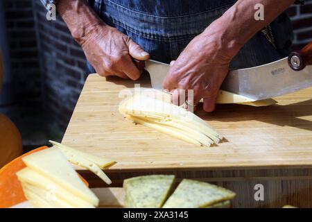 Un homme coupe des fromages au marché du fromage à Alkmaar., Alkmaar, pays-Bas Banque D'Images