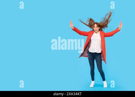 Plein portrait de la taille du corps d'une jeune femme gingembre joyeuse attrayante sautant, s'amusant isolé sur un fond bleu Banque D'Images