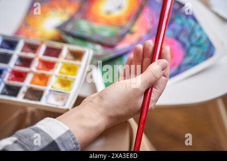 Femme tenant la brosse à portée de main. Palette d'aquarelles. Procédé de dessin artistique. Étude graphique de la formation professionnelle. Atelier de classe de passe-temps de peinture. Équipement d'atelier Banque D'Images